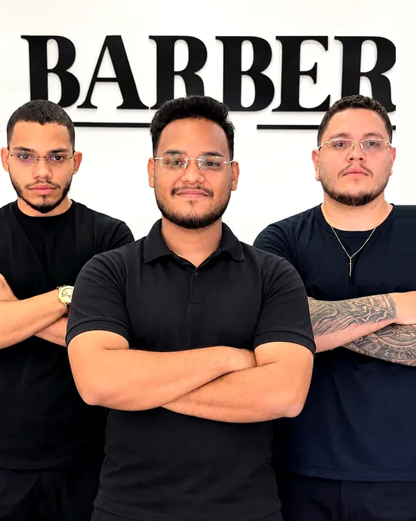 A equipe da J Barber Club na frente do letreiro da barbearia, em Caucaia (CE)
